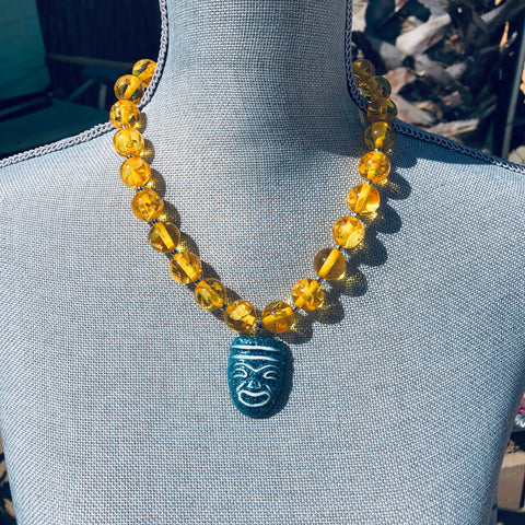 Teal tiki mask on yellow Lucite beaded necklace